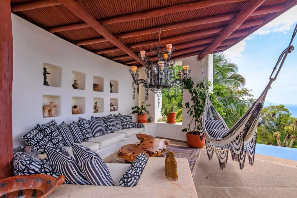 Outdoor seating area with a hammock, cushions, and a chandelier, overlooking the ocean in Puerto Vallarta
